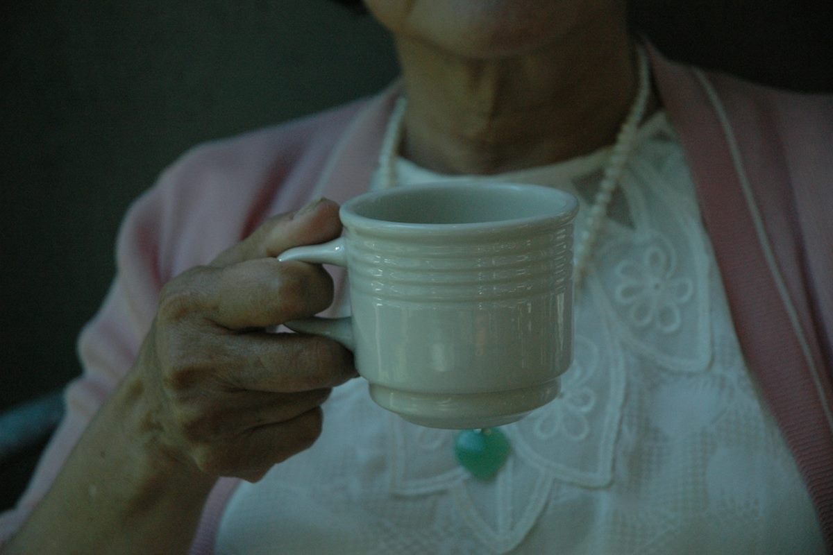 An older woman holding a warm mug of tea in the morning