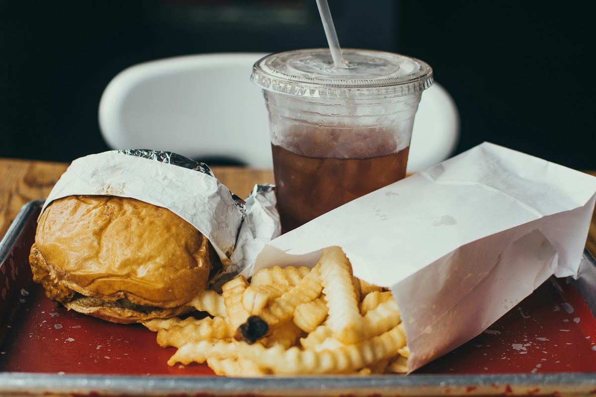 A fast-food meal of a burger, fries and a sugary cola on a tray